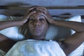 Young scared and stressed black african American woman depressed on bed upset unable to sleep suffering hangover headache feeling Royalty Free Stock Photo