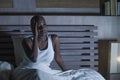 Young scared and stressed black african American woman depressed on bed upset unable to sleep suffering hangover headache feeling Royalty Free Stock Photo