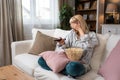 Young scared woman sitting alone at home on the floor watching scary horror movie on the television. Disgusted animal lover female Royalty Free Stock Photo