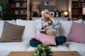 Young scared woman sitting alone at home on the floor watching scary horror movie on the television. Disgusted animal lover female Royalty Free Stock Photo