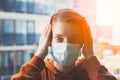 Young scared woman wearing surgical mask because of viruses and air pollution in the city