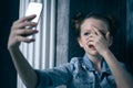 Young scared and worried teenager girl holding mobile phone as internet stalked victim abused and cyberbullying or cyber Royalty Free Stock Photo