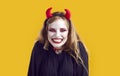 Young scary Caucasian woman with white makeup and horns invites you to Halloween party celebrations