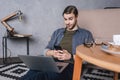 young sceptic man looking at laptop while sitting