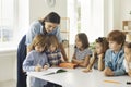 School teacher helping her happy little students who are writing in their notebooks Royalty Free Stock Photo