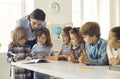 Young school teacher helping her happy little students who are learning to write Royalty Free Stock Photo