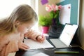 Young schoolgirl doing her homework with digital tablet at home. Child using gadgets to study. Education and distance learning for Royalty Free Stock Photo