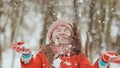 A young schoolgirl joyfully throws a snowball and breaks it with a palm when it falls. Emotions of joy. Winter fun in