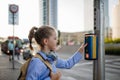 Schoolgirl standing at the crosswalk and pressing the crosswalk button. Royalty Free Stock Photo