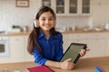 Young Schoolgirl Wearing Headphones Holding Digital Tablet Studying At Home Royalty Free Stock Photo