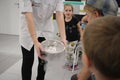 A young scientist in a dressing gown shows children experiments on a tour in the laboratory