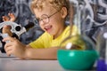 Boy in a yellow T-shirt looks at crystals on microscope stage in the laboratory