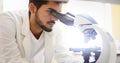 Young scientist looking through microscope in laboratory