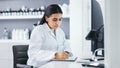 Young scientist using a computer and microscope in a lab. Female pathologist analyzing medical samples while doing