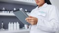 Young scientist using a digital tablet and microscope in a lab. Female pathologist analyzing medical samples while doing