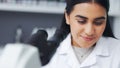 Young scientist using a digital tablet and microscope in a lab. Female pathologist analyzing medical samples while doing