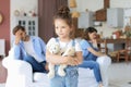 Young scolded parents sitting opposite each other on couch while little defenseless daughter upset looking at camera