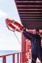 Young seafarer with lifebuoy on the cargo ship.