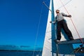 Young seaman on a sailboat standing on a sail boom. Captain of the yacht in the open sea.