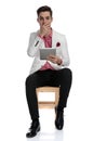 Young seated businessman reading amazing news on his tablet