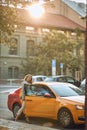 Young businesswoman opening door of a cab, looking at camera