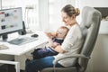 Young self employed mother working at home and taking care of he Royalty Free Stock Photo