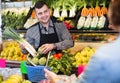 Young seller helping customer to buy vegetables Royalty Free Stock Photo