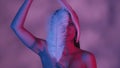 Close up shot of a seminaked young woman touching her face with two feathers in blue and pink color scheme and shadowed Royalty Free Stock Photo