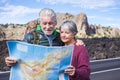 Young senior people enjoy travel and active lifestyle together - couple of old man and woman looking a map on the road -