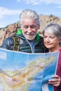 Young senior people enjoy travel and active lifestyle together - couple of old man and woman looking a map on the road - Royalty Free Stock Photo