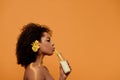 Young sensual african american woman with artistic make-up and gerbera in hair drinking milk from bottle Royalty Free Stock Photo