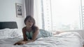 Young sensual brunette woman lies on the bed, temptation near panoramic window in apartment with city view Royalty Free Stock Photo