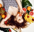 Young sensual curly woman in leopard swimsuit is lying surrounded by fresh ripe summer fruits, enjoying strawberry Royalty Free Stock Photo