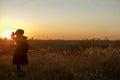 Young sensual woman in black coat and hat  standing in the golden autumn field in the evening on sunset Royalty Free Stock Photo