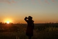 Young sensual woman in black coat and hat  standing in the golden autumn field in the evening on sunset Royalty Free Stock Photo