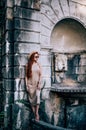 Young sensual woman tourist in sunglasses summer dress stands barefooted on ancient palace balcony balustrade, parapet