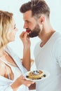 Sensual woman feeding boyfriend with strawberry while holding plate with pancakes Royalty Free Stock Photo