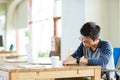 Young serious asian man writing in notebook and using laptop