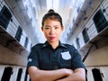 Young serious and attractive Asian Chinese guard woman standing at State penitentiary prison hall wearing police uniform in crime