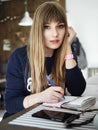 Young serious attractive young woman with pen in hand thinking on plans and writing list to do in notepad enjoying Royalty Free Stock Photo