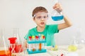 Young serious boy in safety goggles doing chemical experiments in laboratory