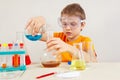 Young serious boy in safety goggles studies chemical practice in laboratory