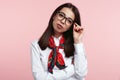 Young confident brunette business female wearing white shirt and scarf, holding her eyeglasses isolated over pink background Royalty Free Stock Photo