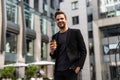 Business, hot drinks and people and concept - young serious businessman with paper coffee cup over office building Royalty Free Stock Photo