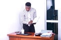 Young serious businessman writing in notebook while looking on digital tablet screen Royalty Free Stock Photo