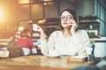 Young serious businesswoman in glasses sitting in cafe at wooden table and talking on cell phone. Royalty Free Stock Photo