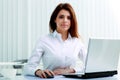 Young serious businesswoman sitting at the table with laptop Royalty Free Stock Photo