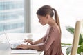 Young serious busy businesswoman sitting at her workplace using Royalty Free Stock Photo