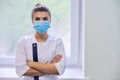 Young serious confident woman doctor in medical mask with folded arms Royalty Free Stock Photo