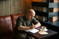 Young serious fashionable man sitting alone in loft-styled cafe Royalty Free Stock Photo